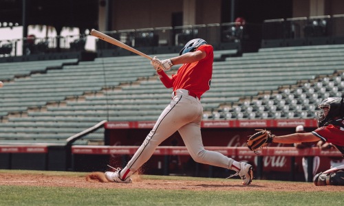 Baseball player swinging bat in empty stadium
